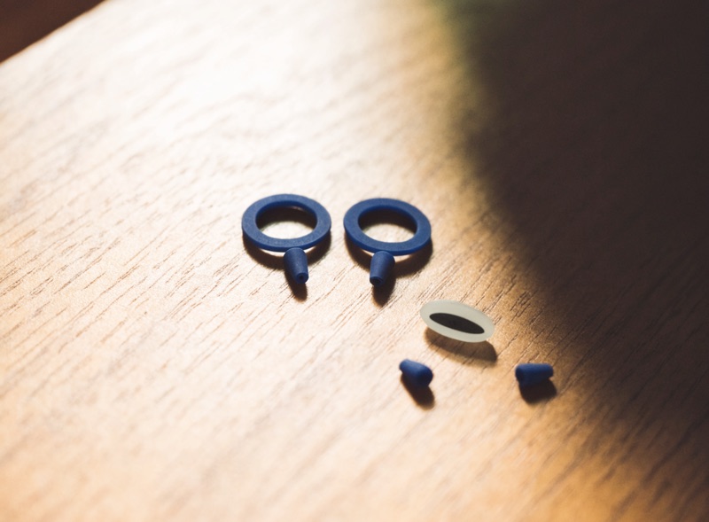 Two navy silicone earplugs and a round case on a felt desk mat
