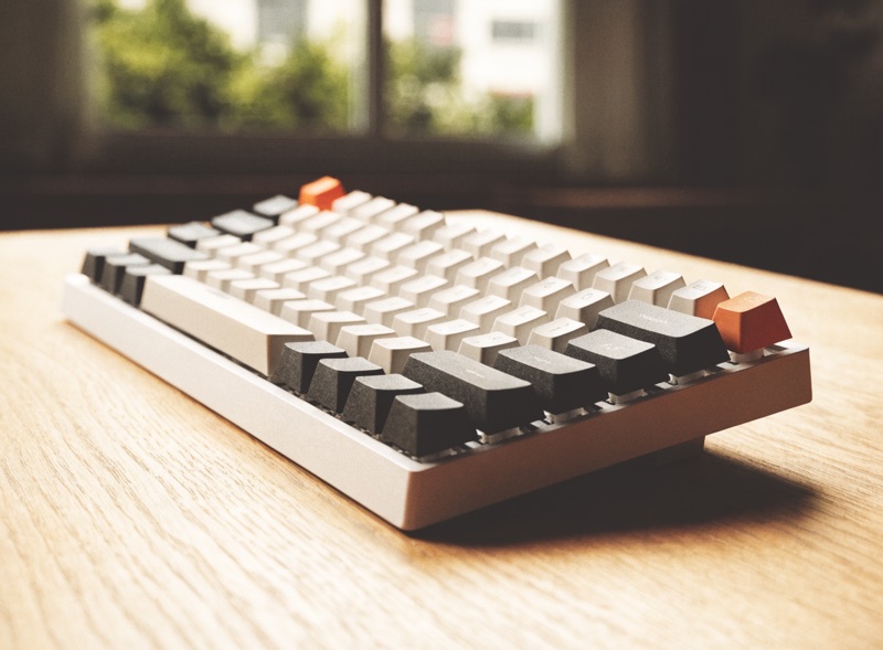 A compact mechanical keyboard with cream keycaps on a desk mat