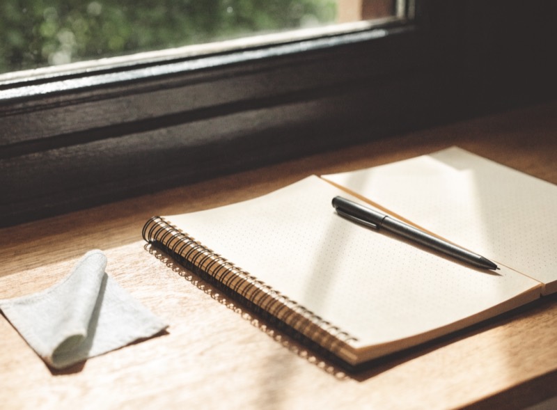 A reusable dot-grid notebook lying open with a pen across the page
