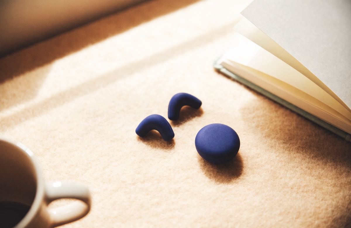 Earplugs and their case resting on a felt desk mat beside a notebook