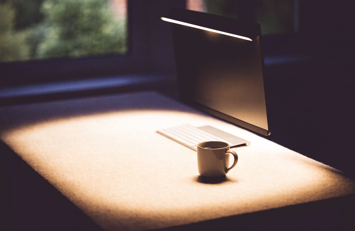A monitor light bar casting a warm pool of light across a desk at dusk